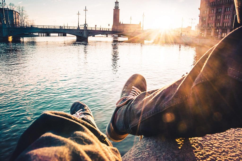person sitting on a ledge overlooking a body of water during an EV road trip in the UK