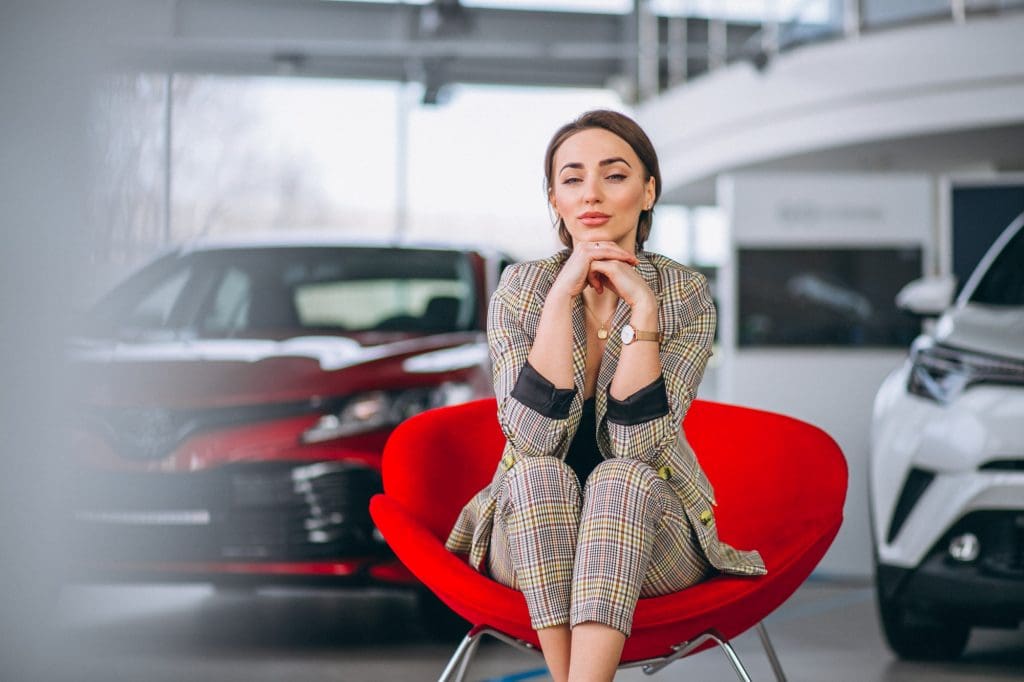 Woman considering cars in a dealership before buying a used electric car