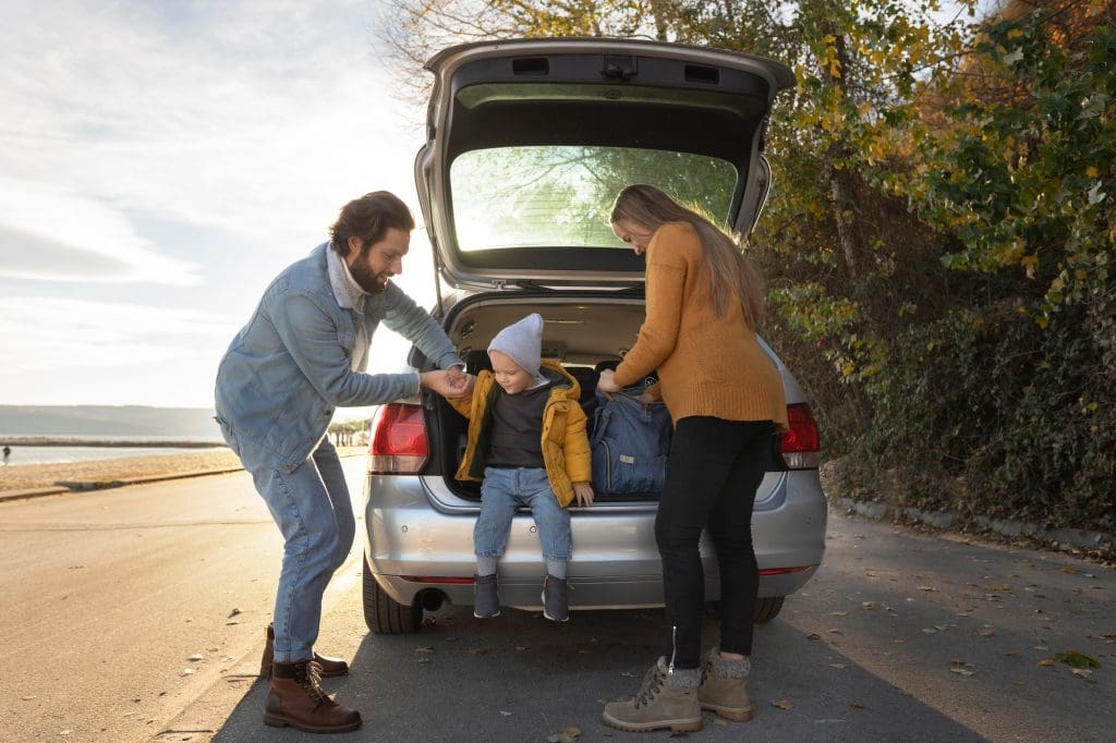 woman and two children are sitting in the trunk of an affordable family EV in the UK, 2025