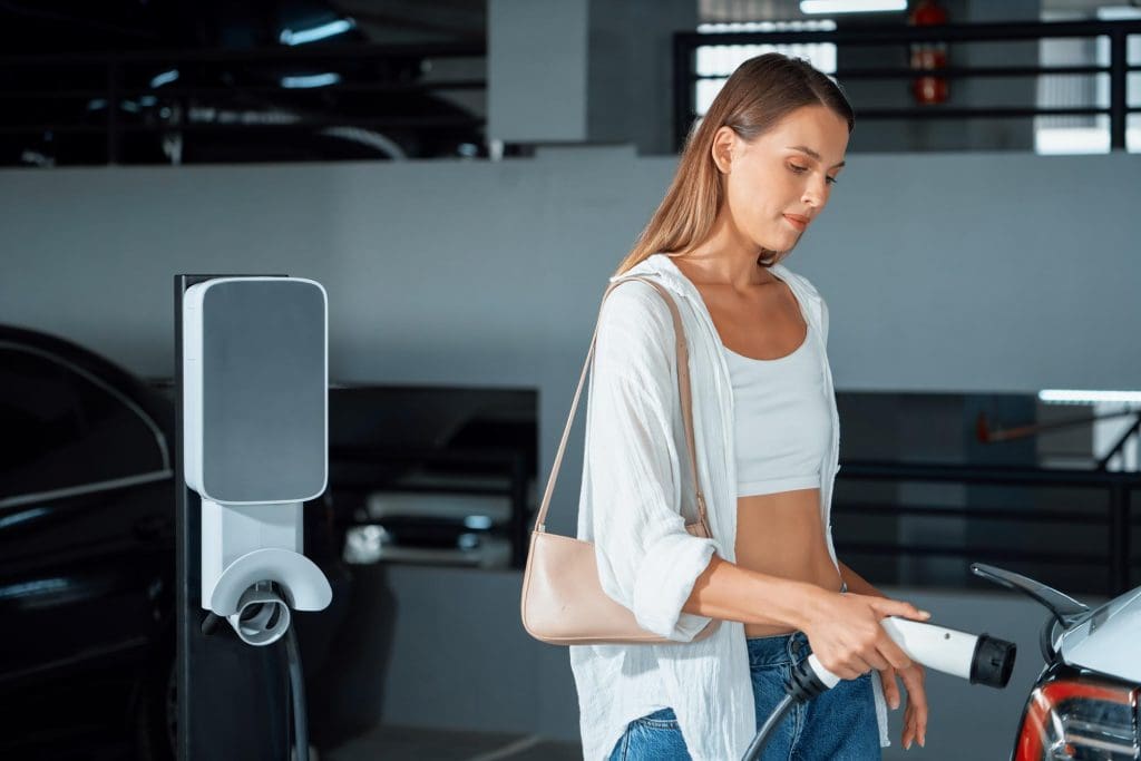 woman standing next to a car in a garage with one-tap EV charging