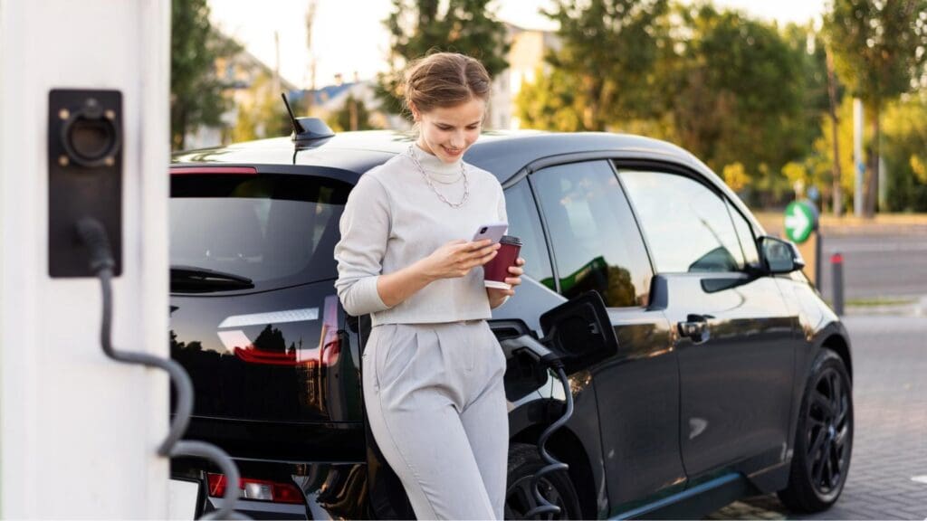 woman standing next to a car looking at her cell phone