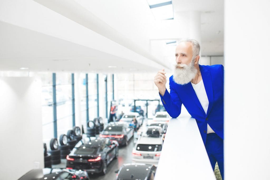 man in a blue jacket standing in a car showroom featuring affordable EVs UK 2025