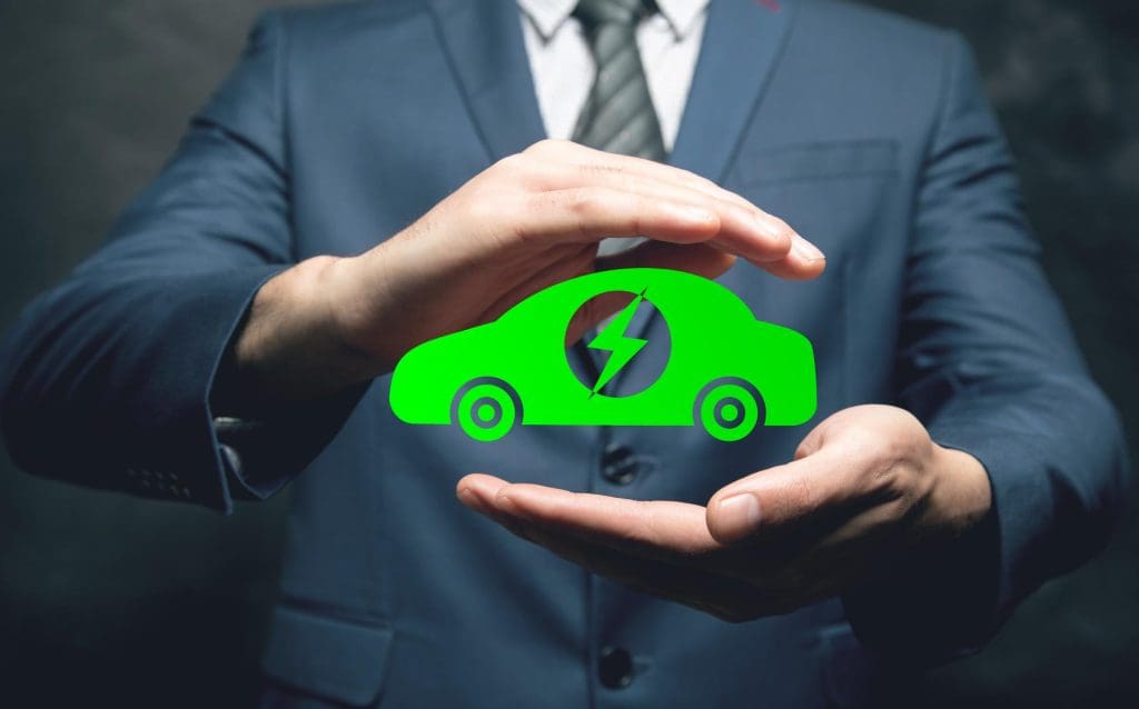Person holding a green electric-car symbol with a lightning bolt between their hands