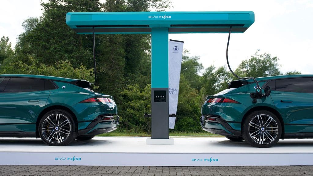 Two electric cars beside a BYD Flash Charging unit during a UK technology demonstration