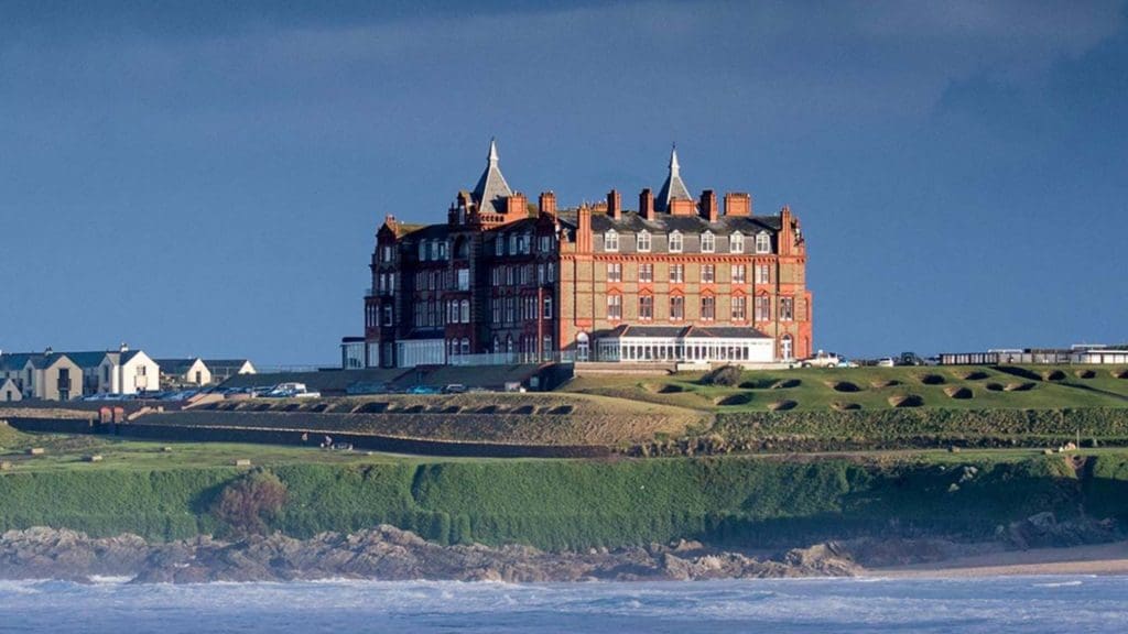 large building sitting on top of a lush green hillside, possibly an EV friendly hotel in the UK
