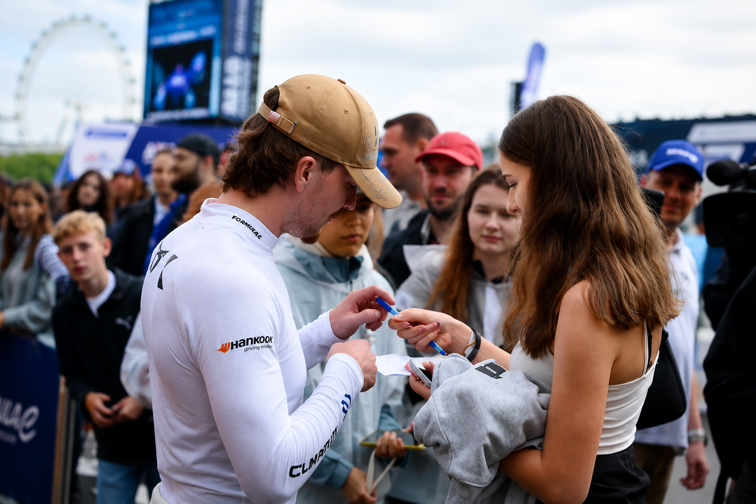 Formula E driver signing an item for a young motorsport supporter at the London E-Prix