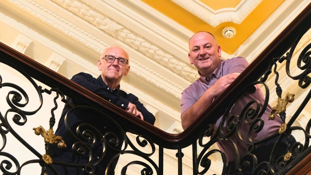 couple of men standing on top of a set of stairs to celebrate ONEEV Marks One Year