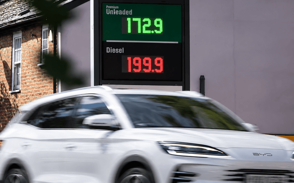 Electric car passing petrol and diesel price signs in the UK