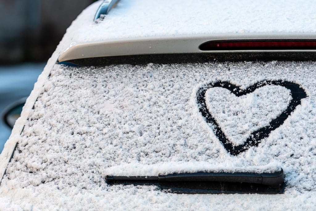 car covered in snow with a heart drawn on it, pre-condition electric car
