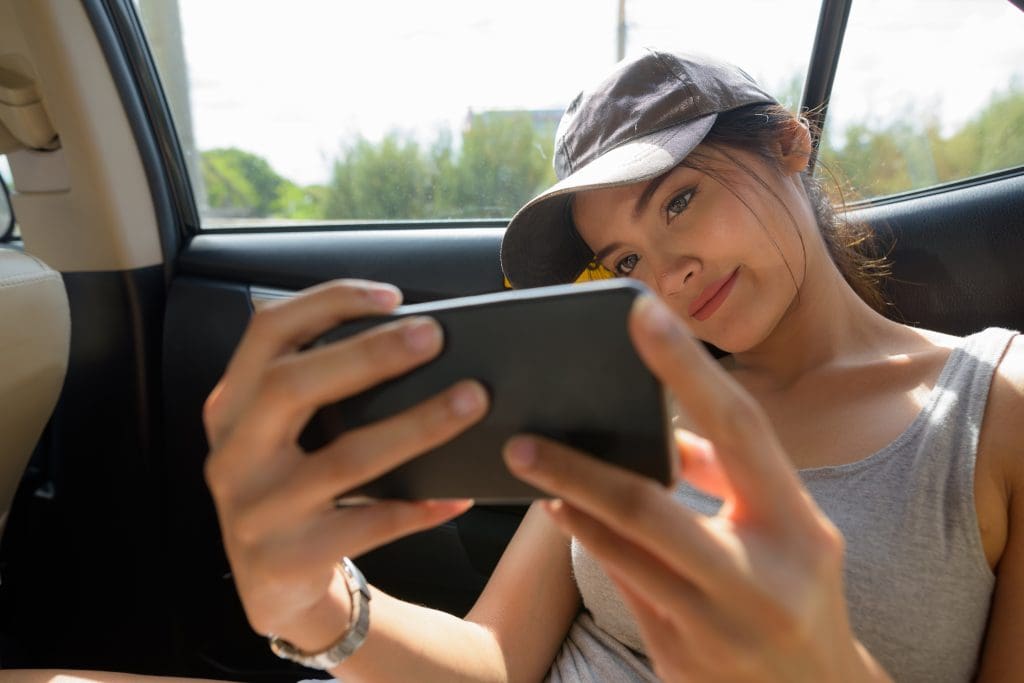 woman sitting in a car looking at a tablet, possibly exploring ev accessories uk