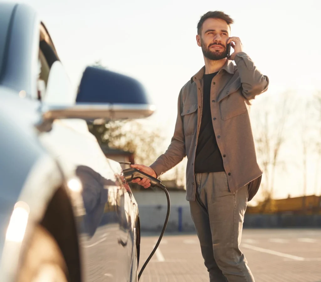man standing next to a car talking on a cell phone