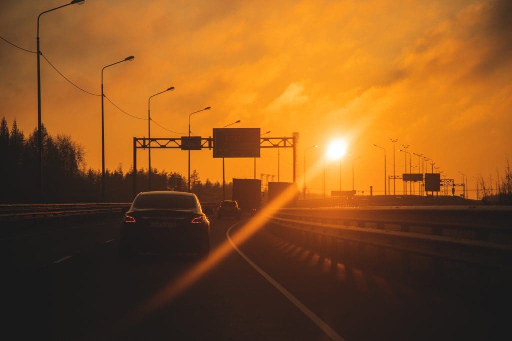 car driving down a highway at sunset