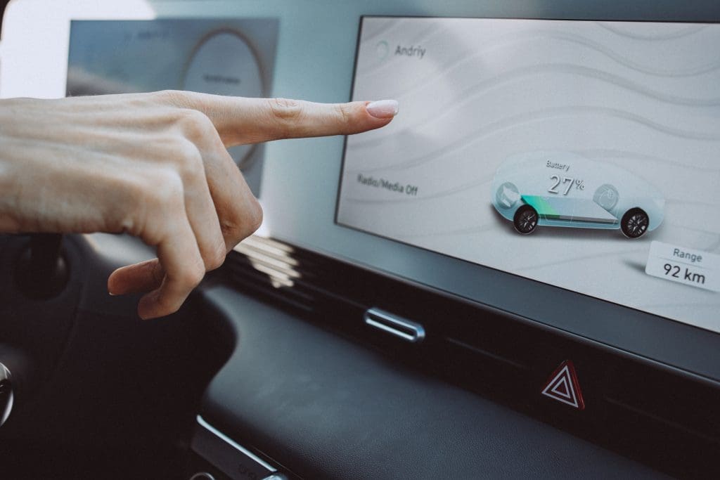 person driving a car and pointing at a screen showcasing ev hidden tech features in the UK
